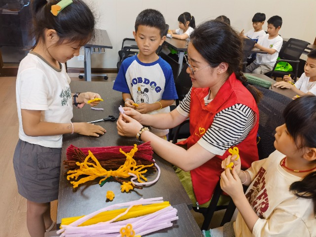 7月12日，在泰州市海陵區(qū)城東街道林湖社區(qū)，泰州市大浦小學(xué)“綠葉”暑期公益班的老師正在教孩子們一起做手工2（拍攝者：泰州市大浦中心小學(xué)  陳惠婷）.jpg
